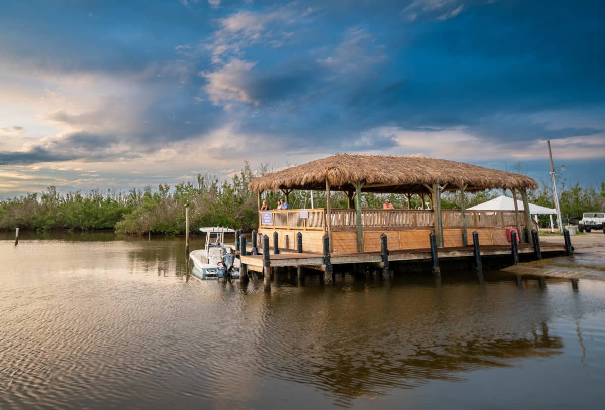 View across a bay looking at a tiki which was built on a dock with a raised wooden floor.